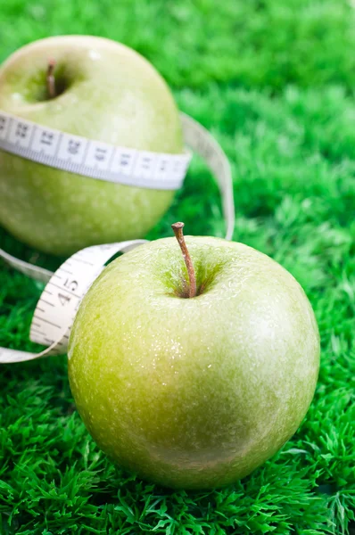 Deux pommes sur herbe avec ruban à mesurer — Photo