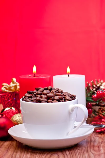 Grains de café de Noël dans une tasse sur une table sur fond rouge Photo De Stock