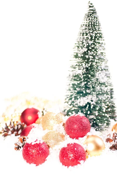 Мини елка с красными и золотыми безделушками на снегу — стоковое фото