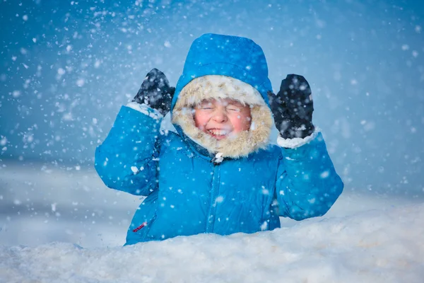 Портрет маленького мальчика, играющего на улице в снегу — стоковое фото