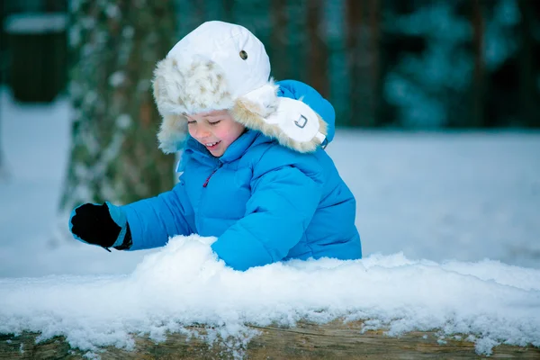 Retrato de um menino brincando com neve ao ar livre em uma floresta de inverno — Fotografia de Stock