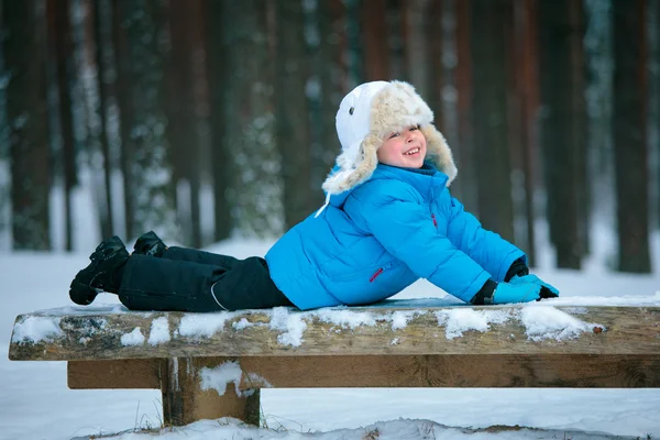 Портрет маленького мальчика, играющего со снегом на открытом воздухе в зимнем лесу — стоковое фото