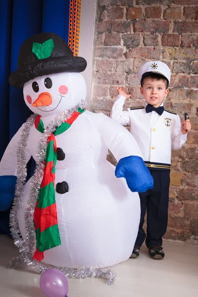 Un niño lindo con un muñeco de nieve —  Fotos de Stock