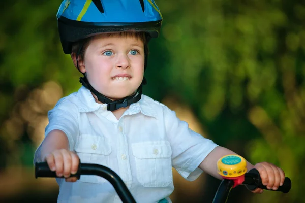 Испуганный мальчик в шлеме на велосипеде — стоковое фото