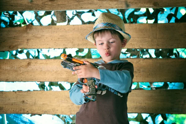 Портрет милого мальчика в шляпе, играющего с пистолетом — стоковое фото