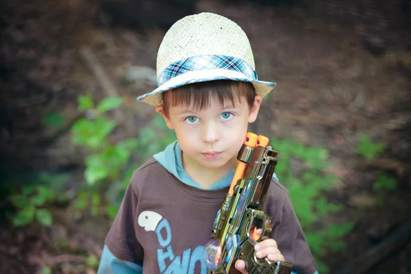 Retrato de um menino bonito em chapéu brincando com uma pistola — Fotografia de Stock
