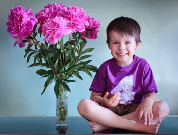 Portrait of a cute boy with peonies bouquet — Stock Photo, Image