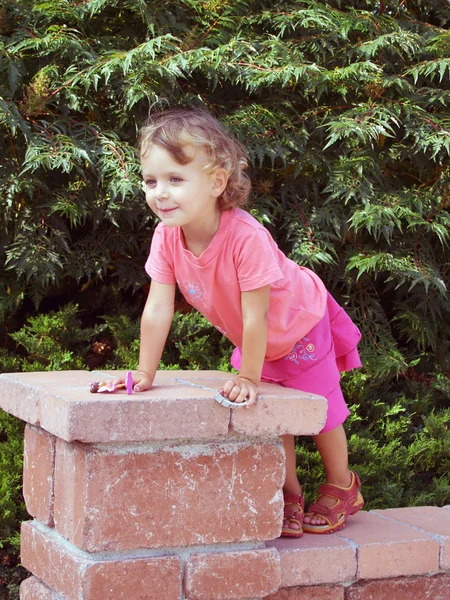 Klein meisje spelen op de muur hek — Stockfoto