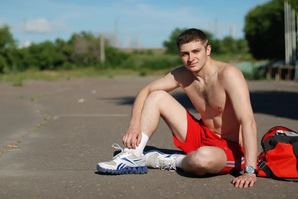 O desportista senta-se no asfalto — Fotografia de Stock