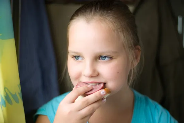 Stock image The girl eats a sandwich with sausage