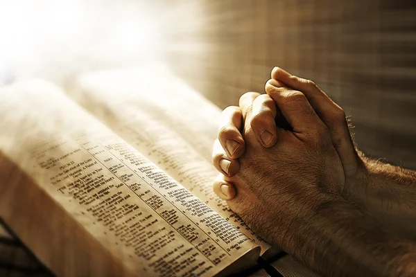 Mans mãos orando sobre a Bíblia — Fotografia de Stock