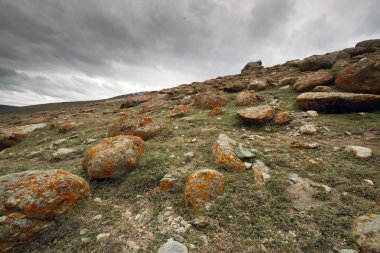 arka planda fırtınalı bulutlar ile turuncu kayalıklar