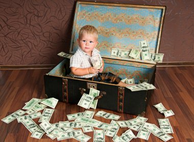 Cute little boy іs sitting in a suitcase with the money