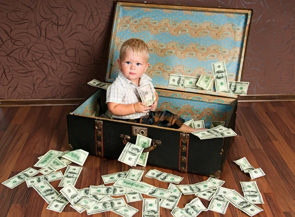 Χαριτωμένο μικρό αγόρι; s κάθεται σε μια βαλίτσα με τα χρήματα — Φωτογραφία Αρχείου