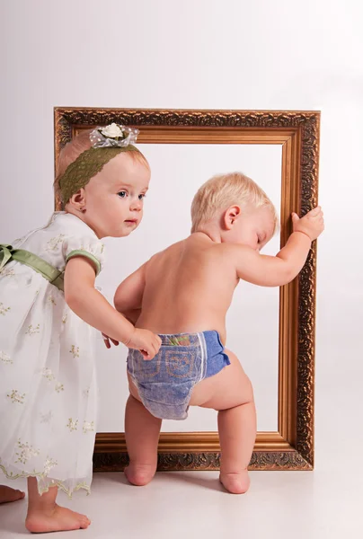 Ein kleiner Junge und ein kleines Mädchen gehen hintereinander durch den Rahmen — Stockfoto
