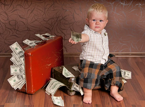 The boy is sitting on a suitcase with the money and handed the money — Stock Photo, Image