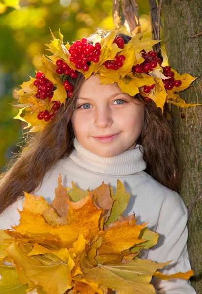Niedliches lächelndes Mädchen in einem Kranz aus rotem Viburnum auf dem Kopf und mit einem Bouque — Stockfoto