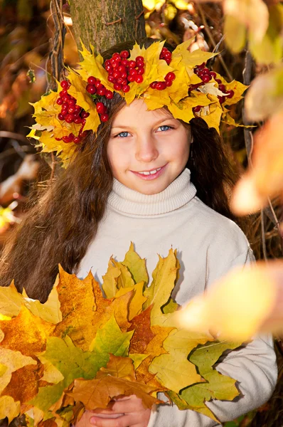 Menina sorridente bonito em uma coroa de viburno vermelho na cabeça e com um buque — Fotografia de Stock