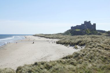 Bamburgh castle with sand dunes and sea clipart