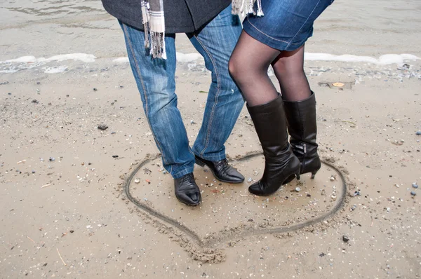 Gambe di felice coulpe nel cuore sulla sabbia della spiaggia autunnale — Foto Stock