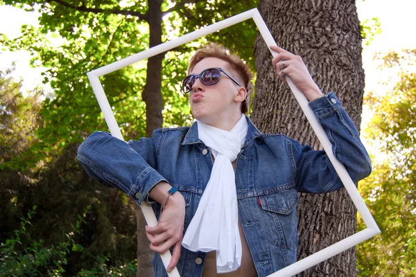 Jonge mens in de tuin met wit frame — Stockfoto