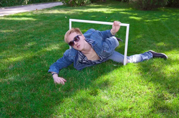 Jonge mens op het groene gras met wit frame — Stockfoto