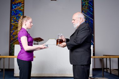 Senior Man Young Woman Holding Wine, Bread, Communion in Church clipart