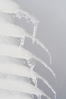 Row of Icicles Hanging off a Roof Gray Sky Background clipart