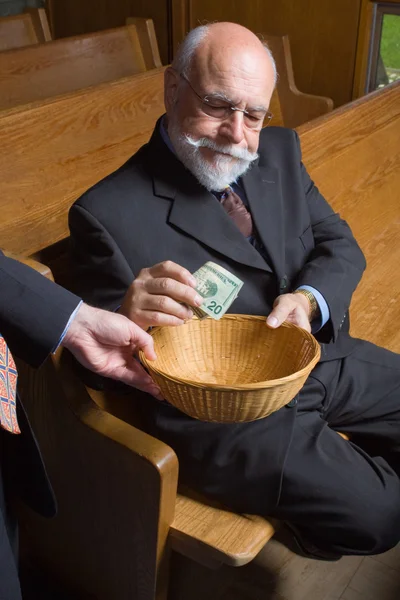 Старший людина вкладає гроші в церковному кошик — стокове фото