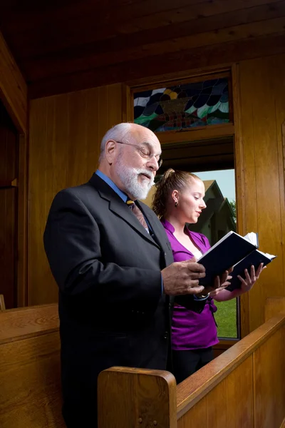 Senior man jonge vrouw kerk zingen liedbundels — Stockfoto