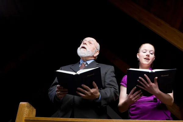 Junge Frau singt in Kirche und hält Gesangbücher hoch — Stockfoto