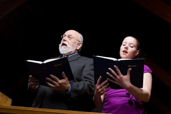 Oudere blanke man jonge vrouw zingen kerk liedbundels — Stockfoto