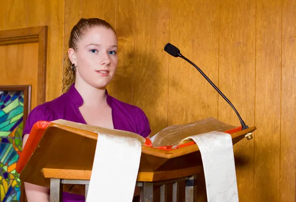 Νεαρή καυκάσιος γυναίκα ανάγνωση από την Αγία Γραφή σε εκκλησία αναλόγιο — Φωτογραφία Αρχείου