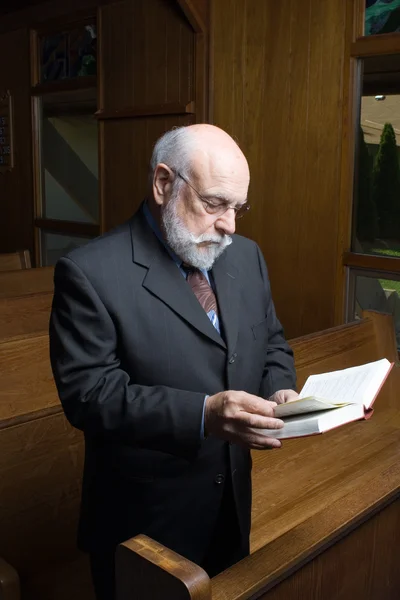 Stehender älterer kaukasischer Mann liest Gesangbuch in Kirchenbank — Stockfoto