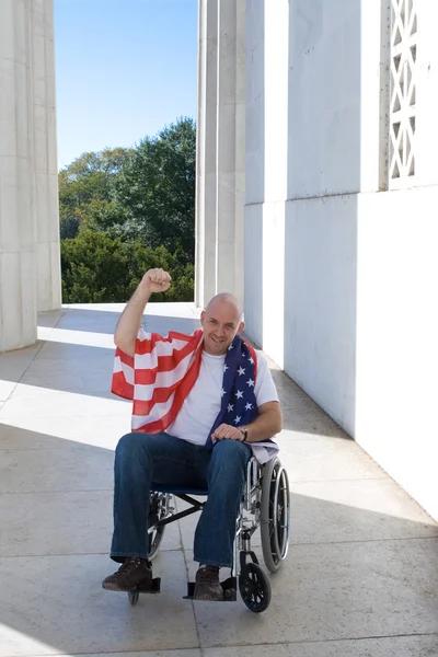 Uomo sedia a rotelle bandiera americana alzato pugno cielo blu — Foto Stock