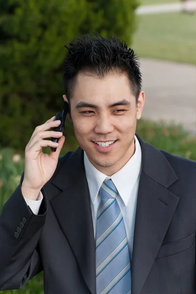 公園の外の携帯電話を保持しているアジア系のビジネスマン — ストック写真