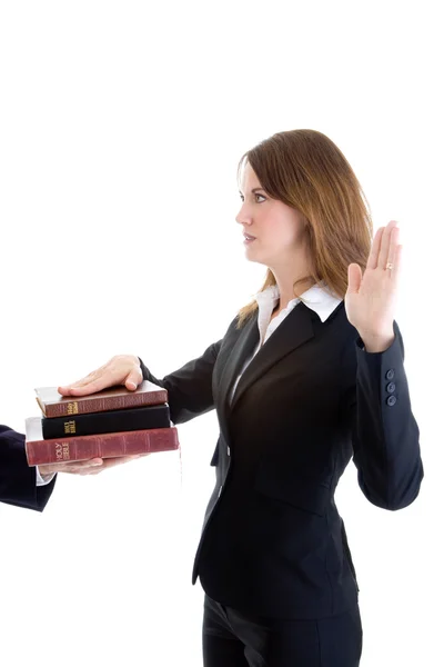 Kaukasische Geschäftsfrau schwört auf einen Stapel Bibeln weißes Isol — Stockfoto