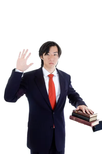 Ásia homem jurando no um pilha de bíblias isolado branco — Fotografia de Stock