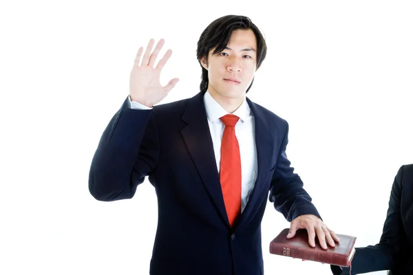 Ásia homem levantado mão jurando no bíblia isolado branco backgroun — Fotografia de Stock