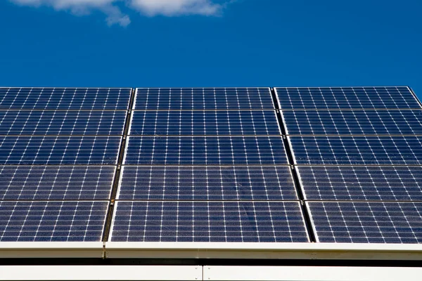 Fila de paneles solares fotovoltaicos en el techo contra el cielo azul —  Fotos de Stock