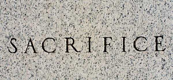 Word "Sacrifice" Carved in Gray Granite Stone — Stock Photo, Image