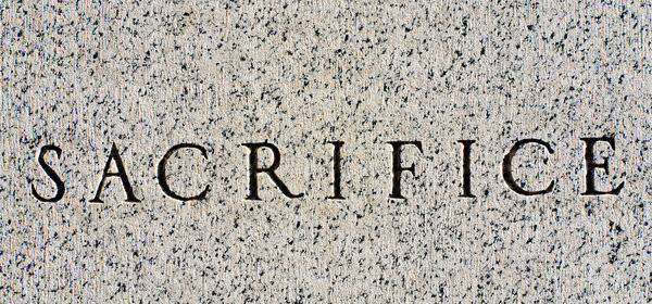 Word "Sacrifice" Carved in Gray Granite Stone
