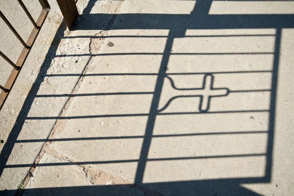 Sombra de um portão com uma cruz nele — Fotografia de Stock