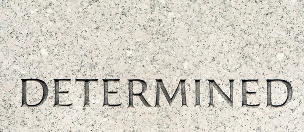 Parola "determinato" intagliato in pietra di granito grigio — Foto Stock