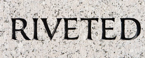 Palabra "remachado" tallado en piedra de granito gris —  Fotos de Stock