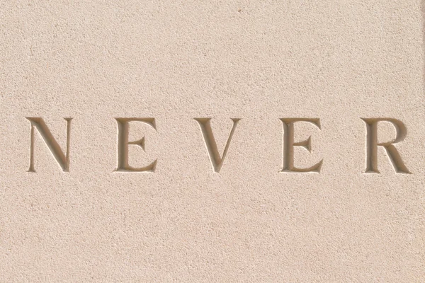 Word "Never" Carved in Sandstone Stone — Stock Photo, Image