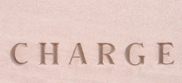 Slovo "charge" vytesaný do pískovce kamene — Stock fotografie