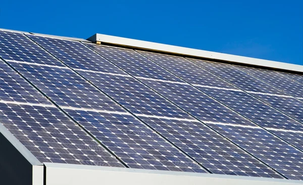 行的太阳能电池板阵列屋顶蓝色天空背景 — 图库照片