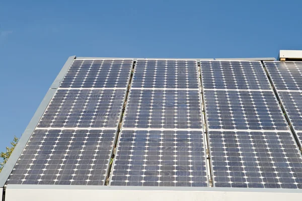 Fila de painéis solares no telhado contra o céu azul — Fotografia de Stock