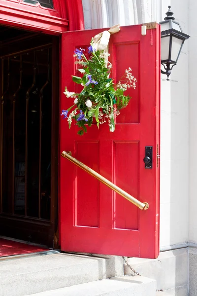 Offene rote Kirchentür mit Osterblumen-Dekoration — Stockfoto